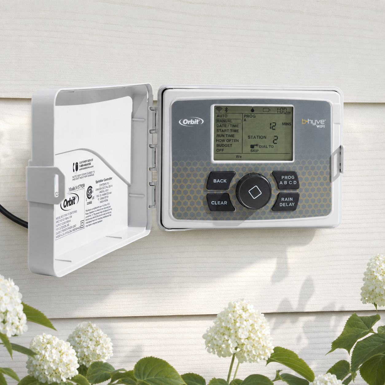 Orbit B-hyve WiFi smart sprinkler controller with its weatherproof housing open, mounted outdoors